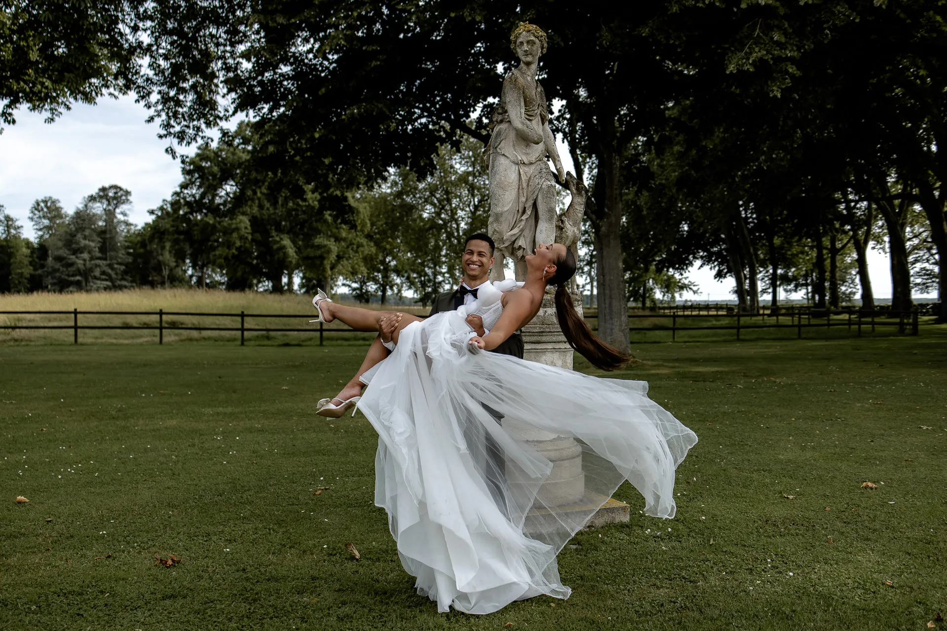 Wedding couple dancing in front of classical statue at Chateau de Varennes France park